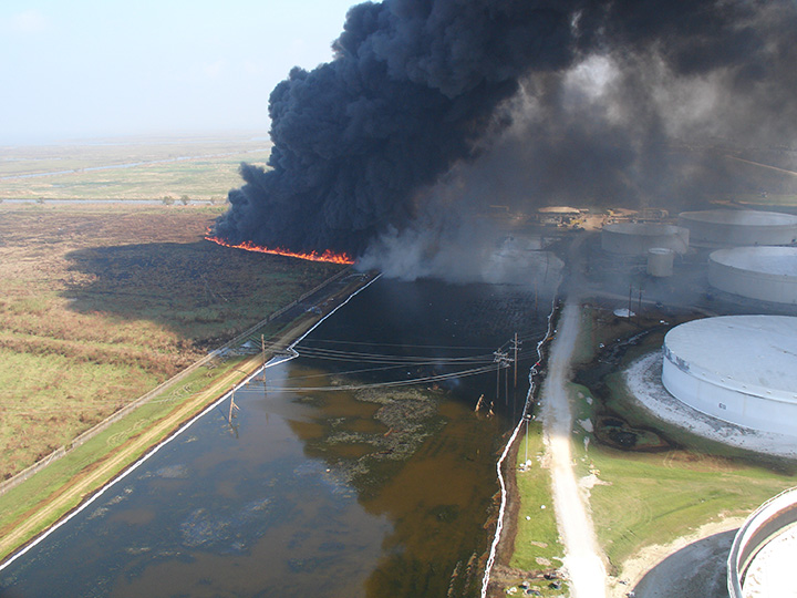 Oil being burned off of the marsh next to oil tanks.