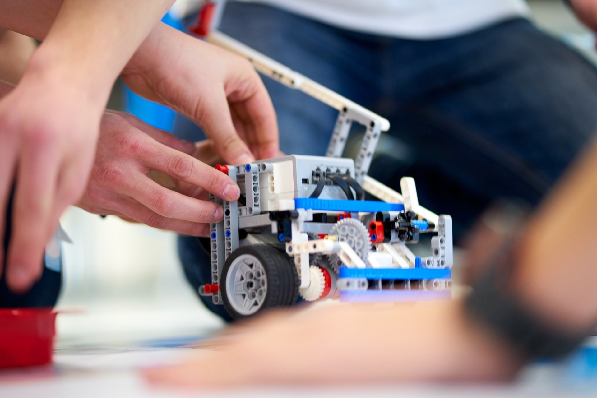 Student hands are seen constructing a machine out of Legos.